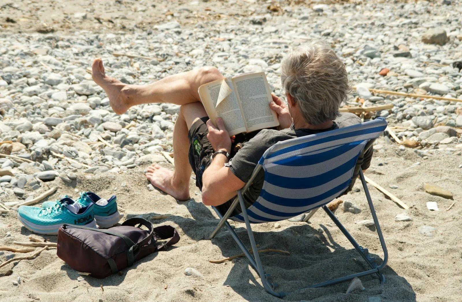 Person relaxing and reading a book on the beach.